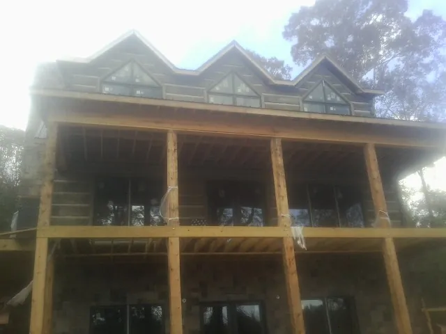 Dormers and porch framing on a large log home under construction — Roof Coating work by our crew in Whitesboro