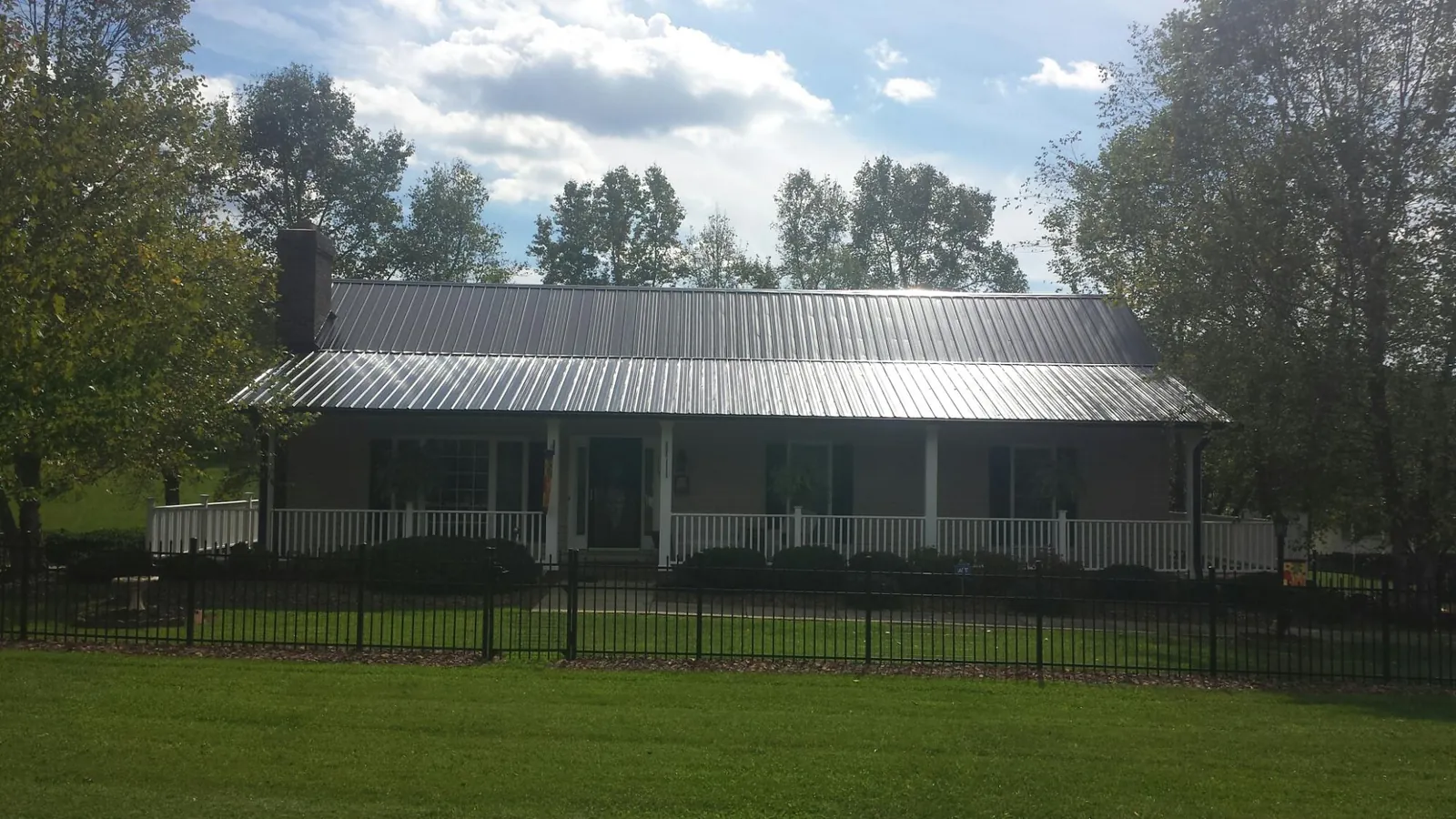 Gray metal roof on a brick ranch with a full width front porch — Gutter Guard Installation work by our crew in Whitesboro